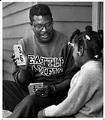 Image of Edwin Wea showing flash card to girl at Black Family Center, Seattle, October 8, 1991