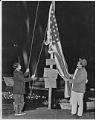 Image of Herman K. Johns Jr. and Billy Frank Jr. lower U.S. flag at protest fishing site, Frank's Landing, Nisqually River, January 21, 1964