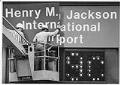 Image of Workers removing sign at SeaTac airport, March 1984