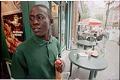Image of William Deng holding a bottle of mango juice outside store, Seattle, 2001