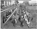 Image of Husky crew team with shells and Indigenous rowers with canoes, La Connor, November 29, 1941