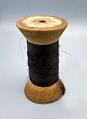 Image of Large spool of black thread, used by Seattle's first childrens' tailor, ca. 1915