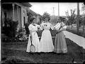 Image of Three women in front yard with tennis rackets, circa 1900