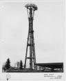 Image of Space Needle under construction, showing partial installation of restaurant ring girder with “sunburst” vanes, October 31, 1961