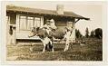 Image of Franz Hardow holding his daughter on a cow in front of Hardow home, Seattle, circa 1926