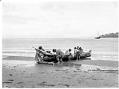 Image of Makah group pulling a canoe on shore at Neah Bay, circa 1900