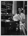 Image of Helene Madison in nurse's uniform seated at desk, circa 1936