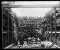 Image of Thomas Barker talking to shipyard workers inside the hull of a wooden ship, 1918