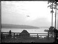 Image of Charles Hamilton's biplane over a lake, March 1910