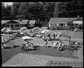 Image of Fourth of July party on NW 120th Street showing neighbors meeting in the street seen from the roof of a nearby house, Seattle, 1961