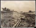Image of Alki Avenue regrade showing water cannon, with flour mill in distance, September 24, 1913